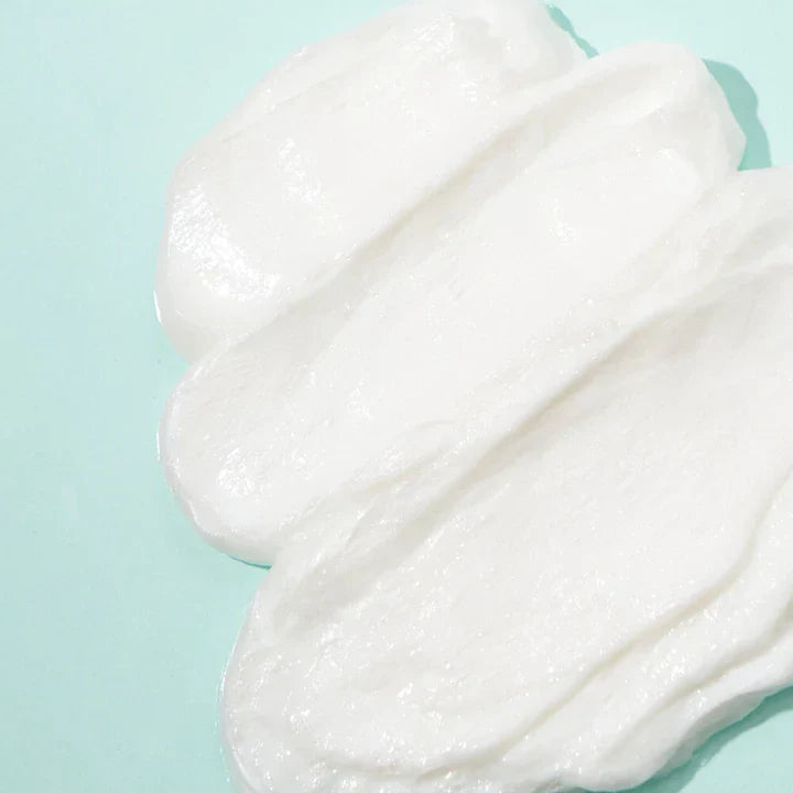 Close-up of Axis-Y Sunday Morning Refreshing Cleansing Foam by AXIS-Y, a smooth, creamy texture spread across a light blue surface. The glossy and soft appearance shows ridges and swirls—ideal for sensitive skin with Aquaxyl care technology.
