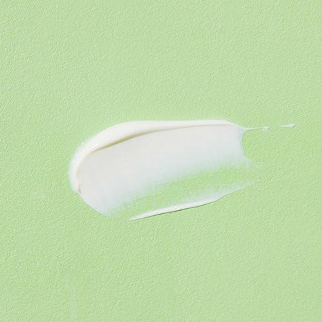 A smear of COSRX Aloe Soothing Sun Cream SPF50+ Pa+++ glistens on a matte light green textured surface, offering a glossy contrast that enhances its protective and hydrating qualities.