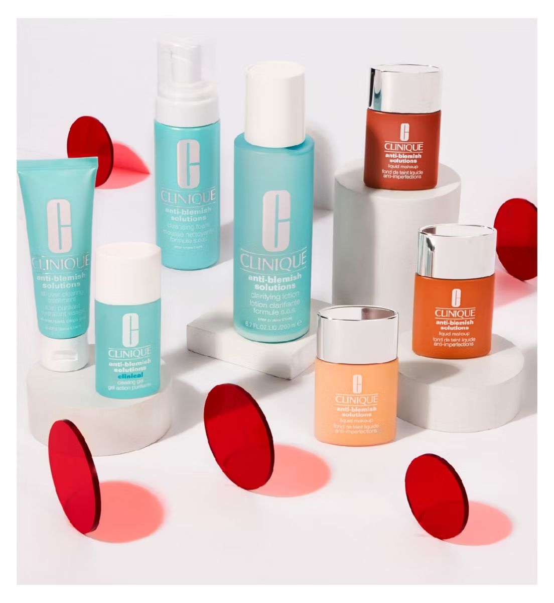 Clinique Anti-Blemish Solution All-Over Clearing Treatment 50ml by Clinique, perfect for acne-prone skin, is shown in a blue and orange bottle on white cylindrical stands with red translucent disks around it.