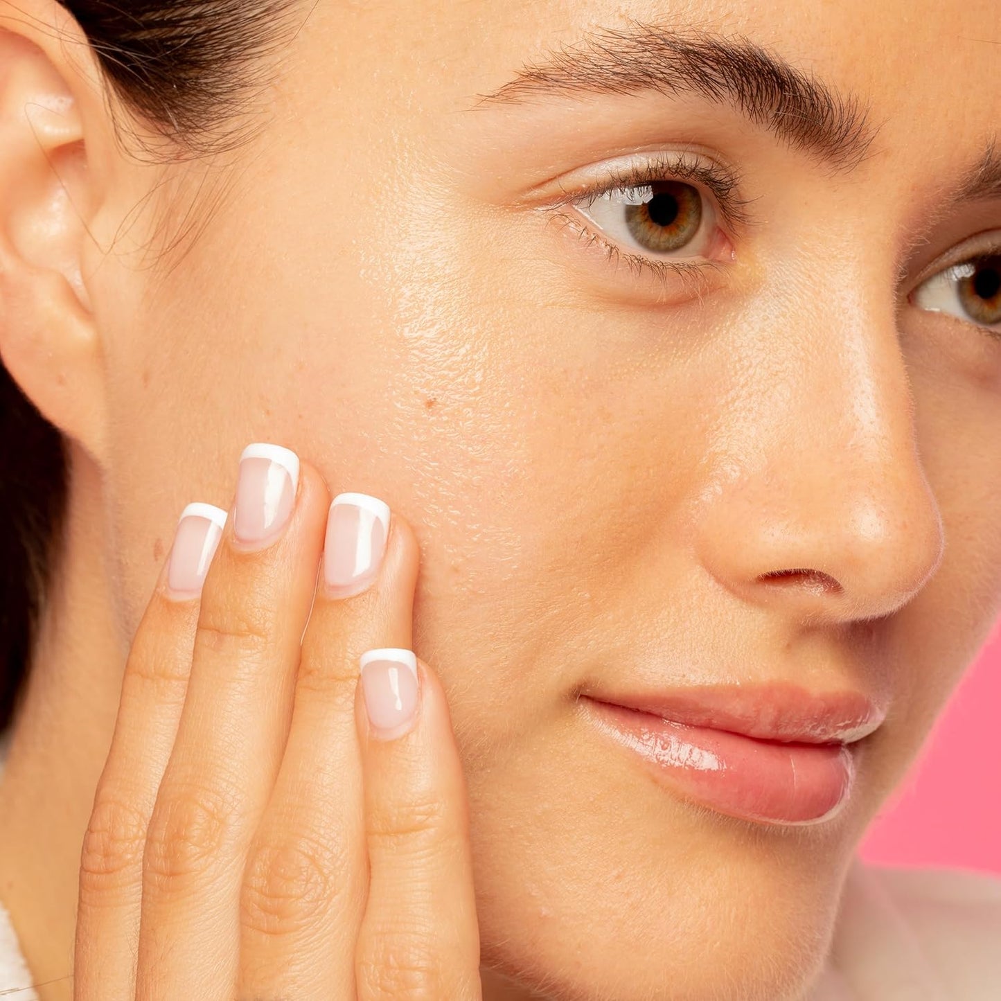 A woman with clear skin touches her cheek, showing off French-tip nails and natural makeup. Against a pink background, she reveals her secret: Good Molecules Daily Brightening Serum 30ml for a radiant glow.