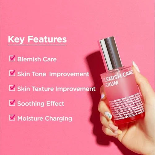 A hand holding ISOI Blemish Care Serum against a pink background, showcasing its benefits like blemish care, skin tone improvement, and hydration boost.