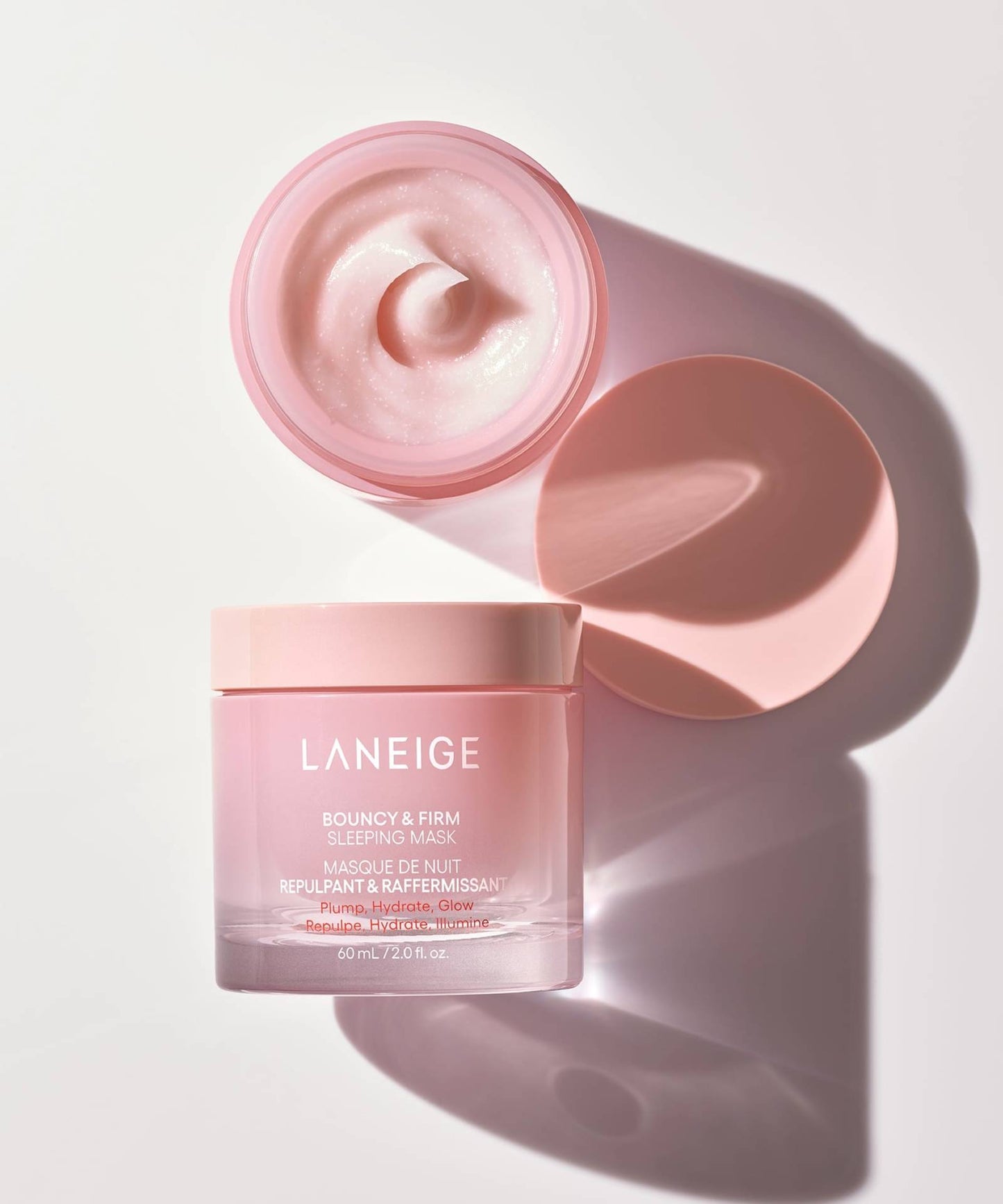 An open jar of Laneige Bouncy & Firm Sleeping Mask showcases a creamy pink substance.