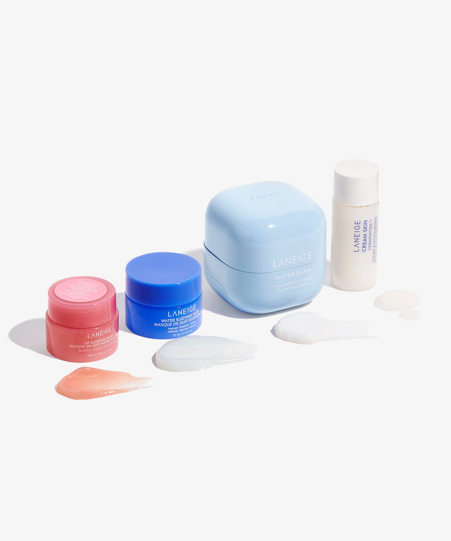 The LANEIGE Icons To Go - 4 Piece set includes hydrating mini essentials in pink, blue, light blue containers, and a white bottle, each featuring a swipe of hyaluronic acid-enriched creams or balms on a pristine white surface.