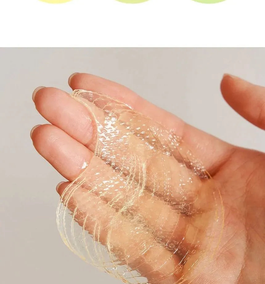 A hand holds a thin, transparent sheet reminiscent of the Goodal Green Tangerine Vita-C Eye Gel Patch 72g. The textured surface drapes over fingers against a plain background, suggesting its revitalizing power.