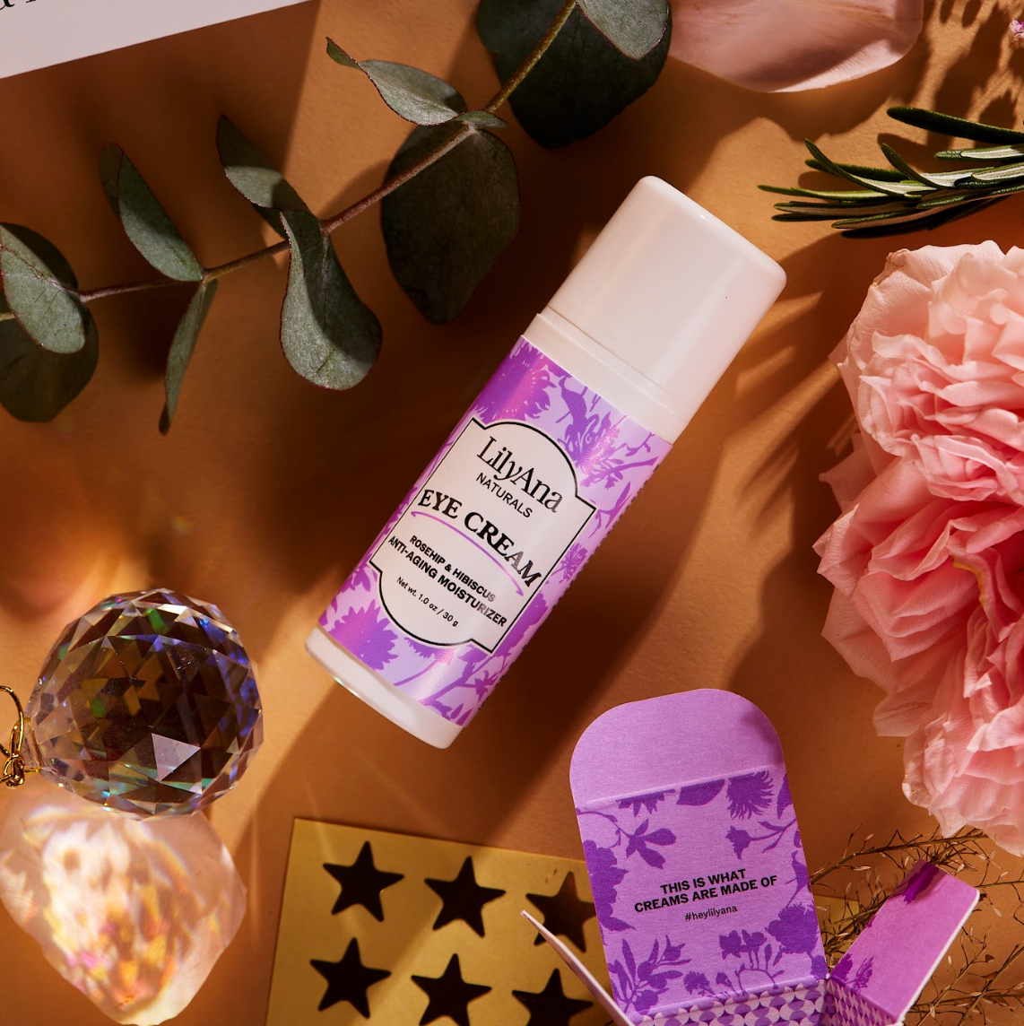 Eye cream bottle with purple label on a decorative surface with flowers and crystals