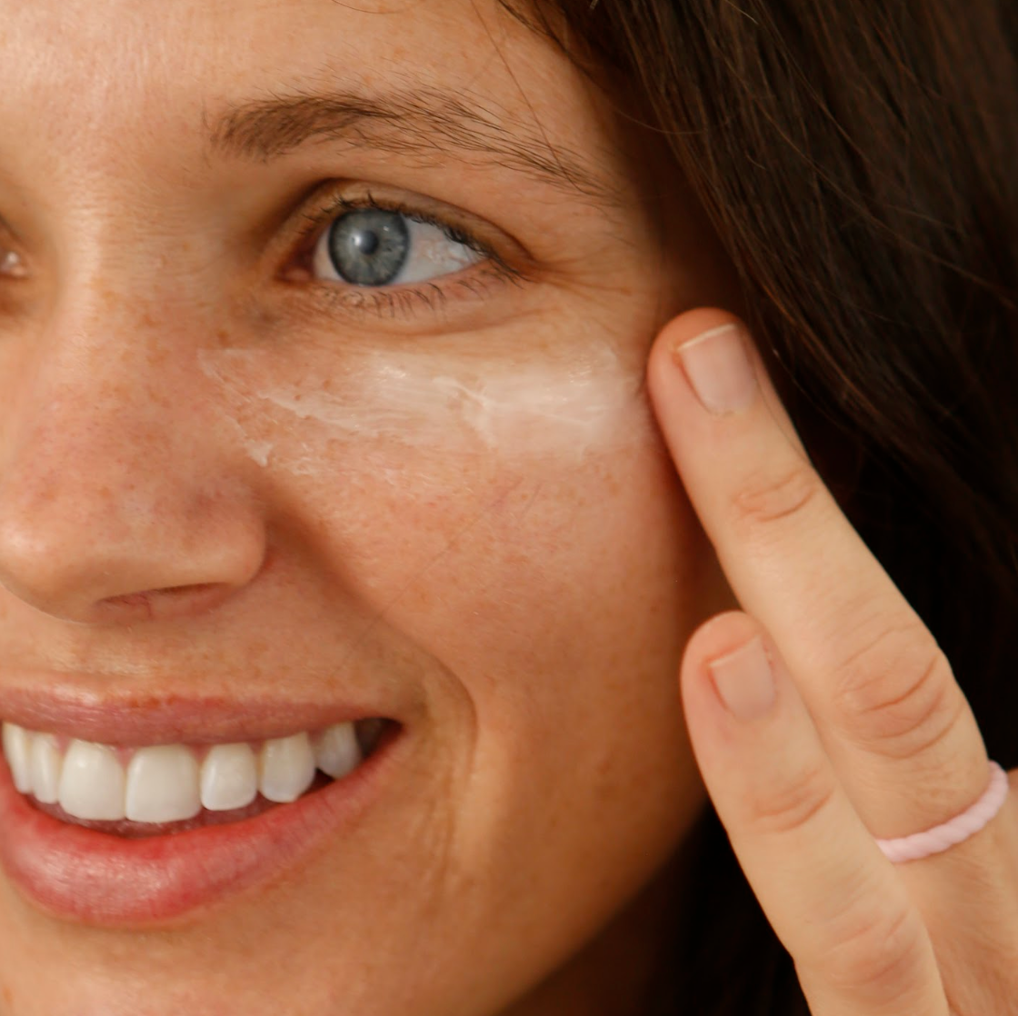 Woman applying cream to her face with a close-up view of her eye area.