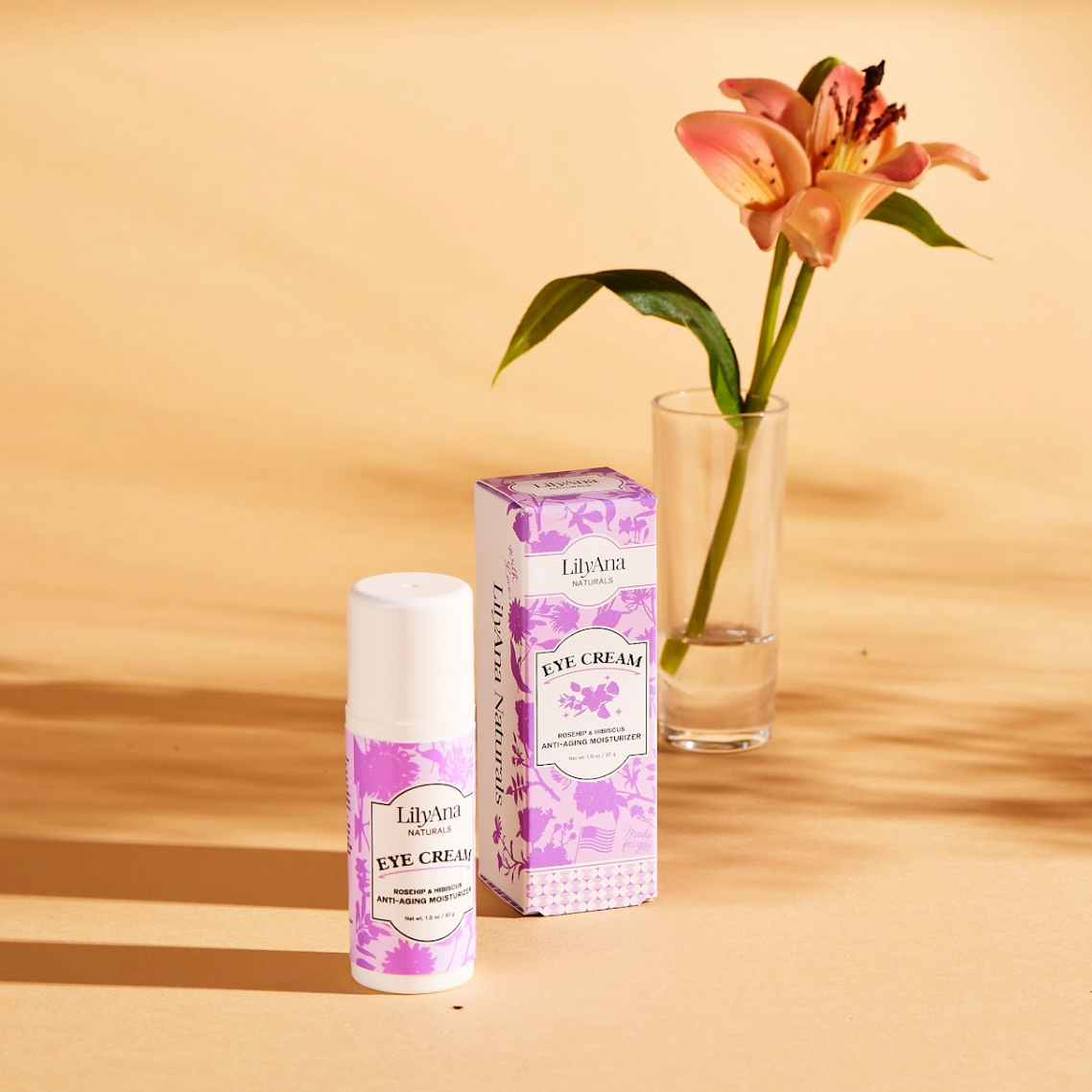 LilyAria eye cream bottle and packaging on a wooden surface with a flower in the background