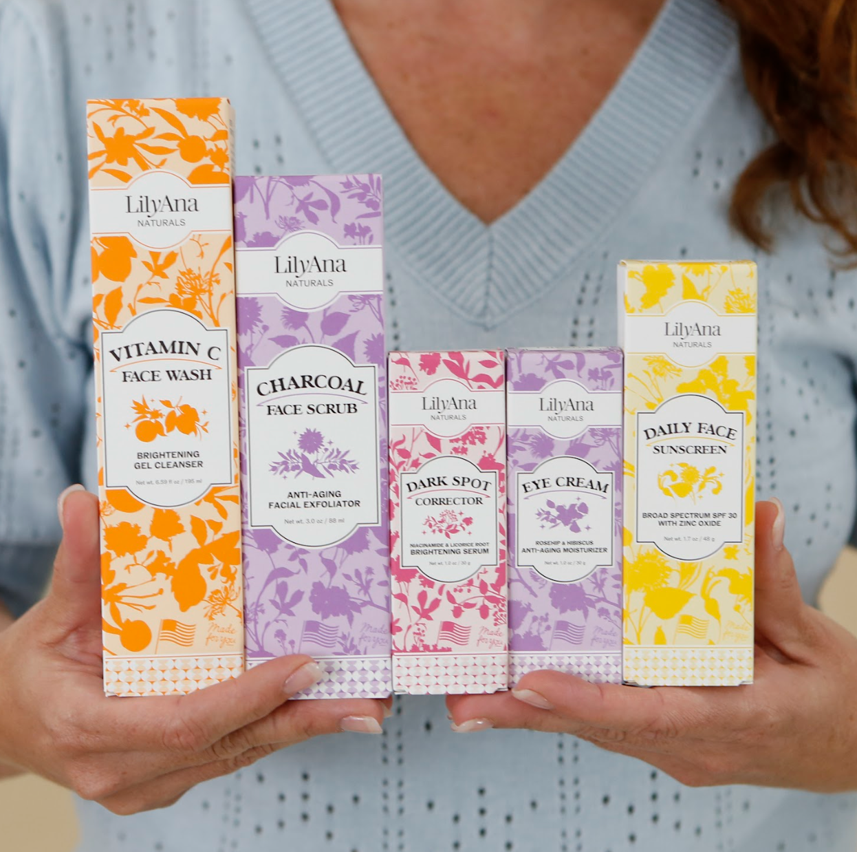 Person holding LilyAna Naturals skincare product boxes.