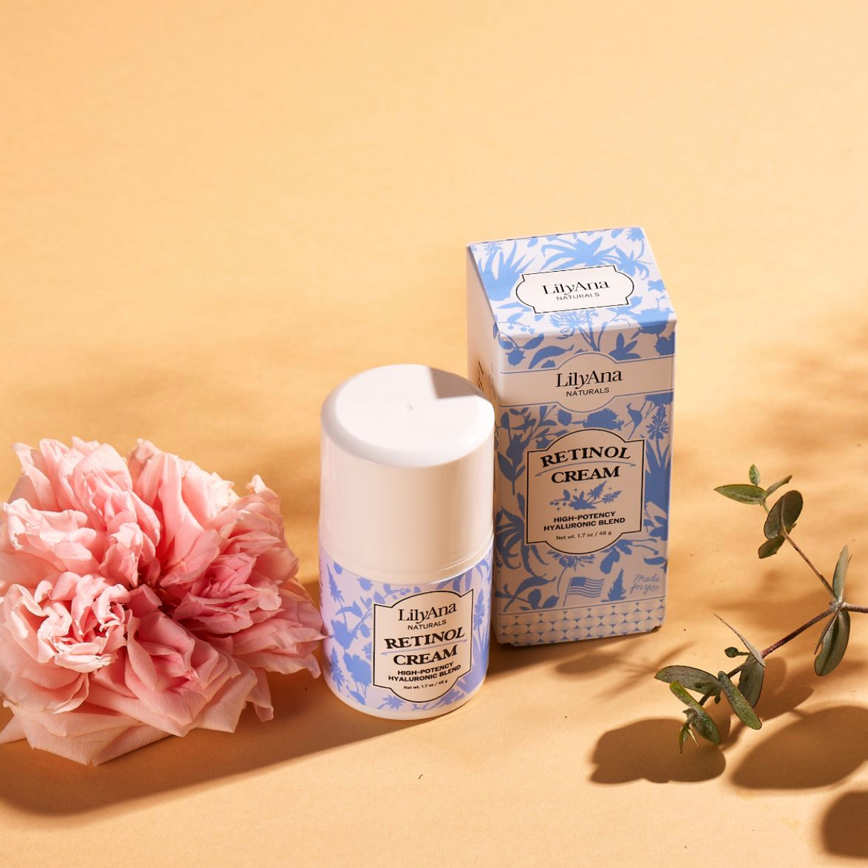 Retinol cream with packaging and a pink flower on a beige background