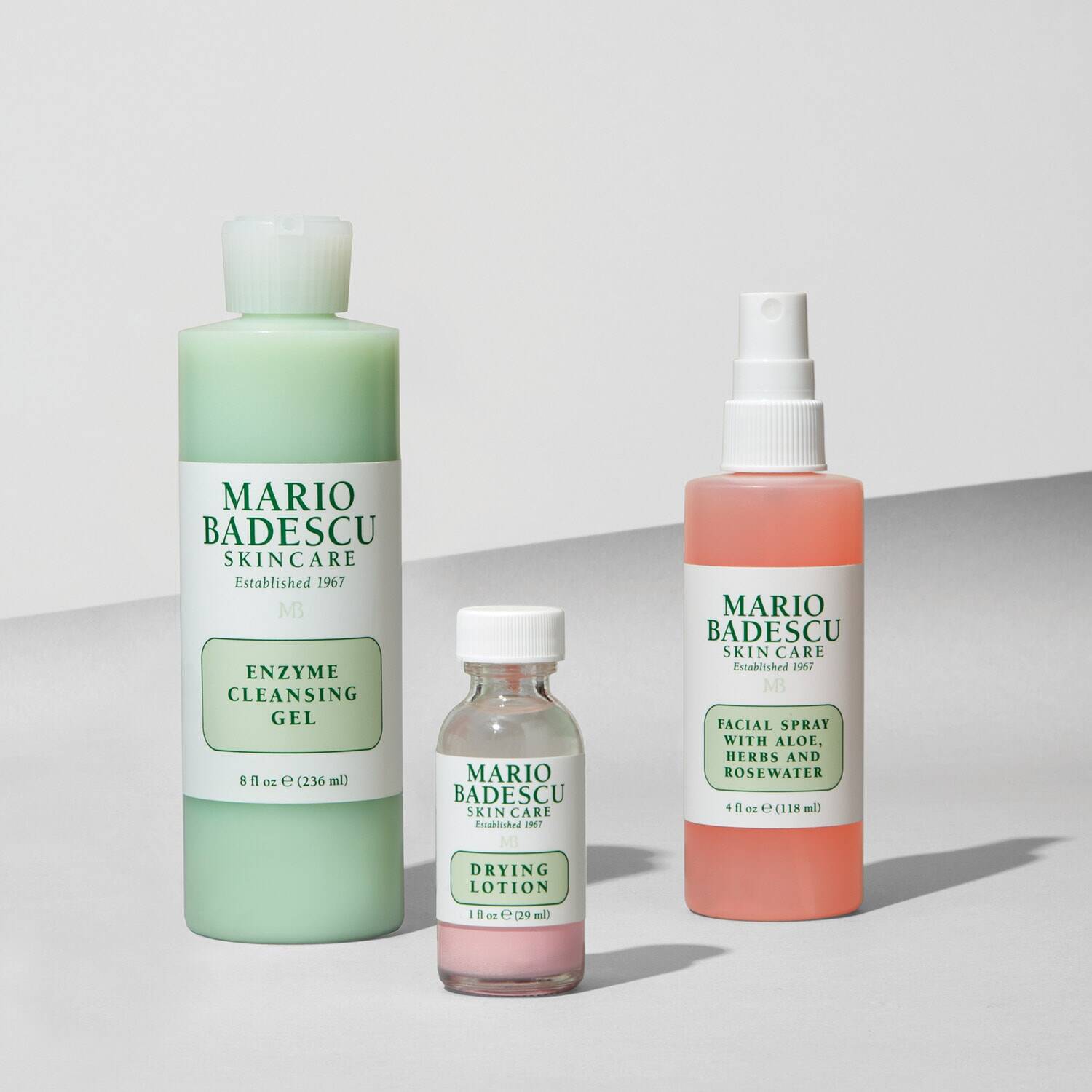 Three Mario Badescu skincare products on a light gray background