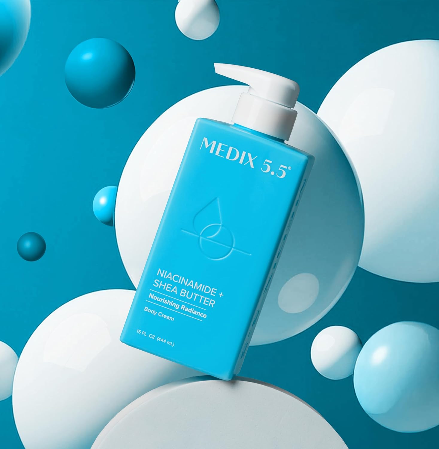 A blue bottle of MEDIX 5.5 Niacinamide + Shea Butter Body Cream (New) with a pump dispenser stands against a blue background, glowing with nourishing radiance amid floating white and blue spheres.