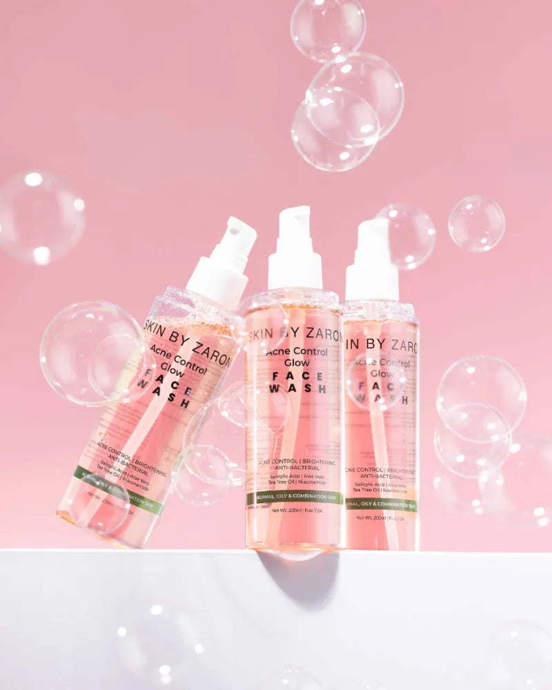 Three bottles of 'Skin by Zaron' face wash on a pink background with bubbles.