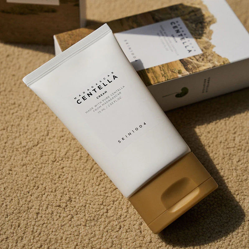 SKIN1004 Centella Cream tube placed on a textured surface next to its packaging, highlighting its calming, moisturizing formula for healthy skin