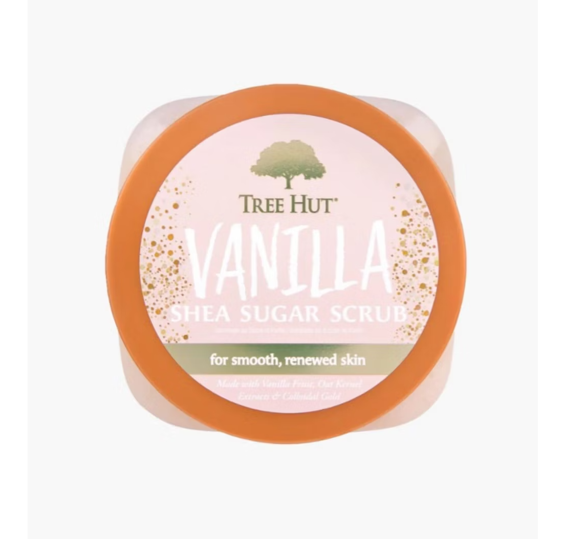 A 510g container of Tree Hut Shea Sugar Body Scrub, Vanilla scent with an orange lid, includes ingredients such as rich vanilla, exfoliant fruit, shea butter kernel essence, and colloidal gold. The label reads for smooth, renewed skin.