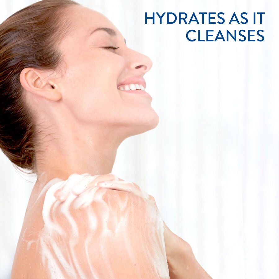 A woman smiles in the shower, applying Cetaphil Ultra Gentle Body Wash to her shoulder. The text HYDRATES AS IT CLEANSES is featured in blue at the top right. The softly blurred background highlights its suitability for sensitive skin needing a moisture barrier.
