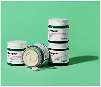 Three jars of Dr.Jart+ Cicapair Tiger Grass Color Correcting Treatment 50ml are on a green surface, one open to reveal the cream. A spatula with the treatment is placed in front, highlighting its suitability for sensitive skin.