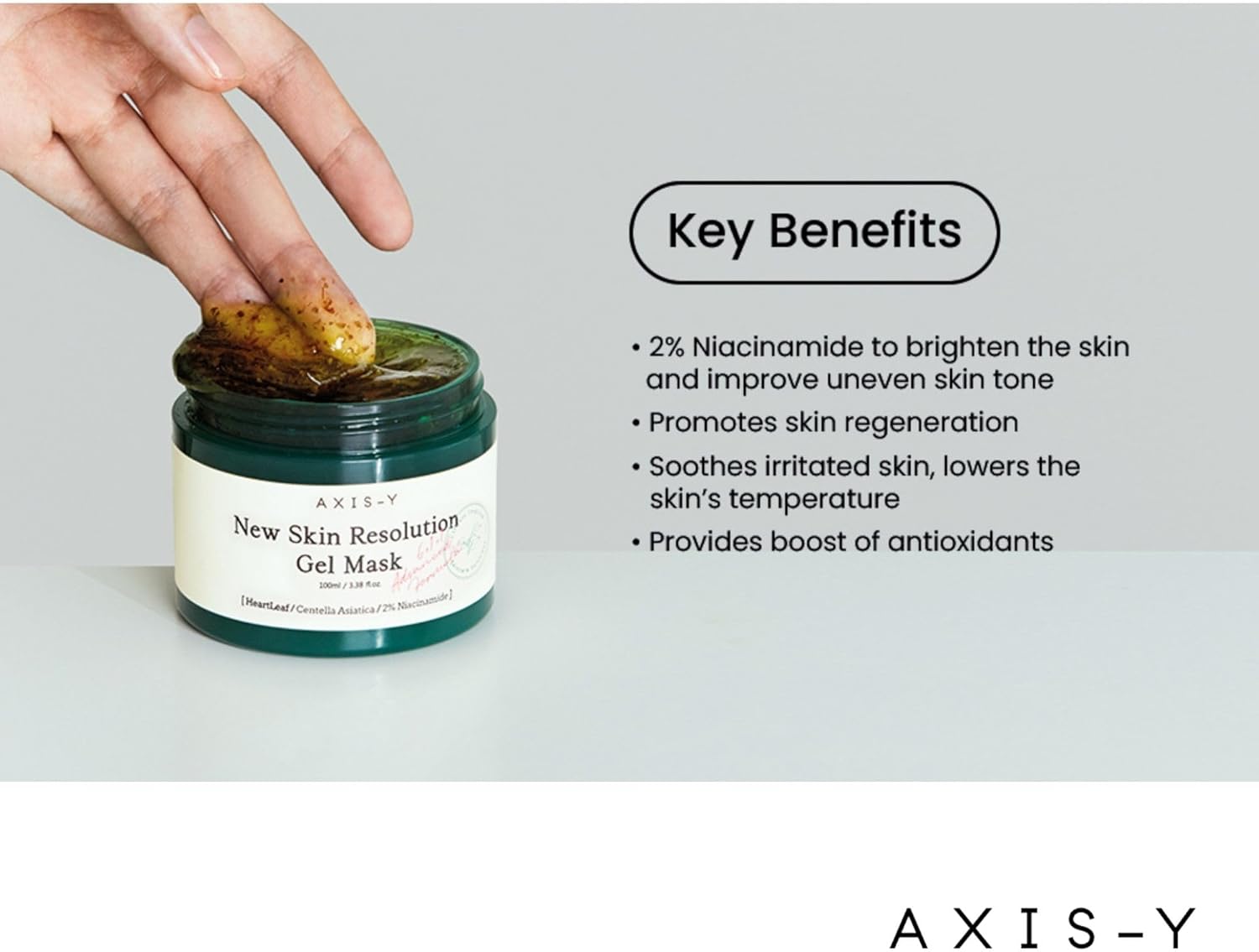 A hand holds a leaf near an open jar of AXIS-Y New Skin Resolution Gel Mask 100ml. Infused with 2% niacinamide, this soothing formula brightens, evens skin tone, promotes regeneration, cools, and offers antioxidant benefits.