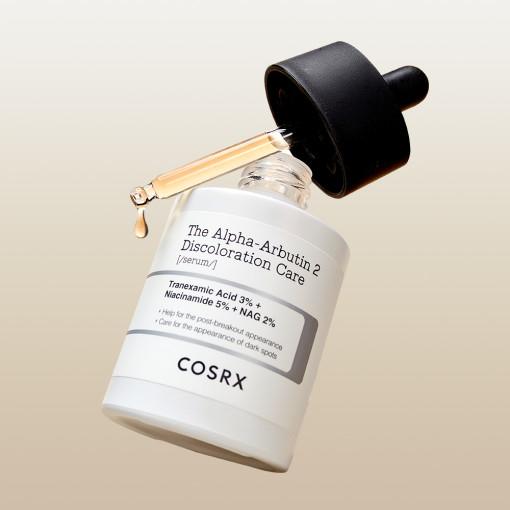 A bottle of COSRX The Alpha-Arbutin 2 Discoloration Care Serum, featuring a dropper. The label highlights Tranexamic Acid 3%, Niacinamide 5%, and NAG 2%. A light gradient background enhances its visual appeal.