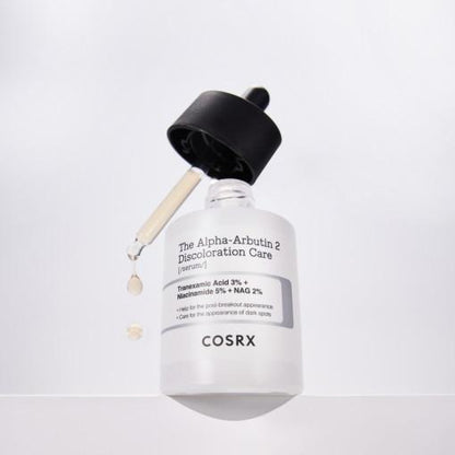 A COSRX The Alpha-Arbutin 2 Discoloration Care Serum 50ml bottle features Tranexamic Acid and Niacinamide, with a dropper for precision. The white bottle has a black cap and highlights its ingredients on a minimalistic label.