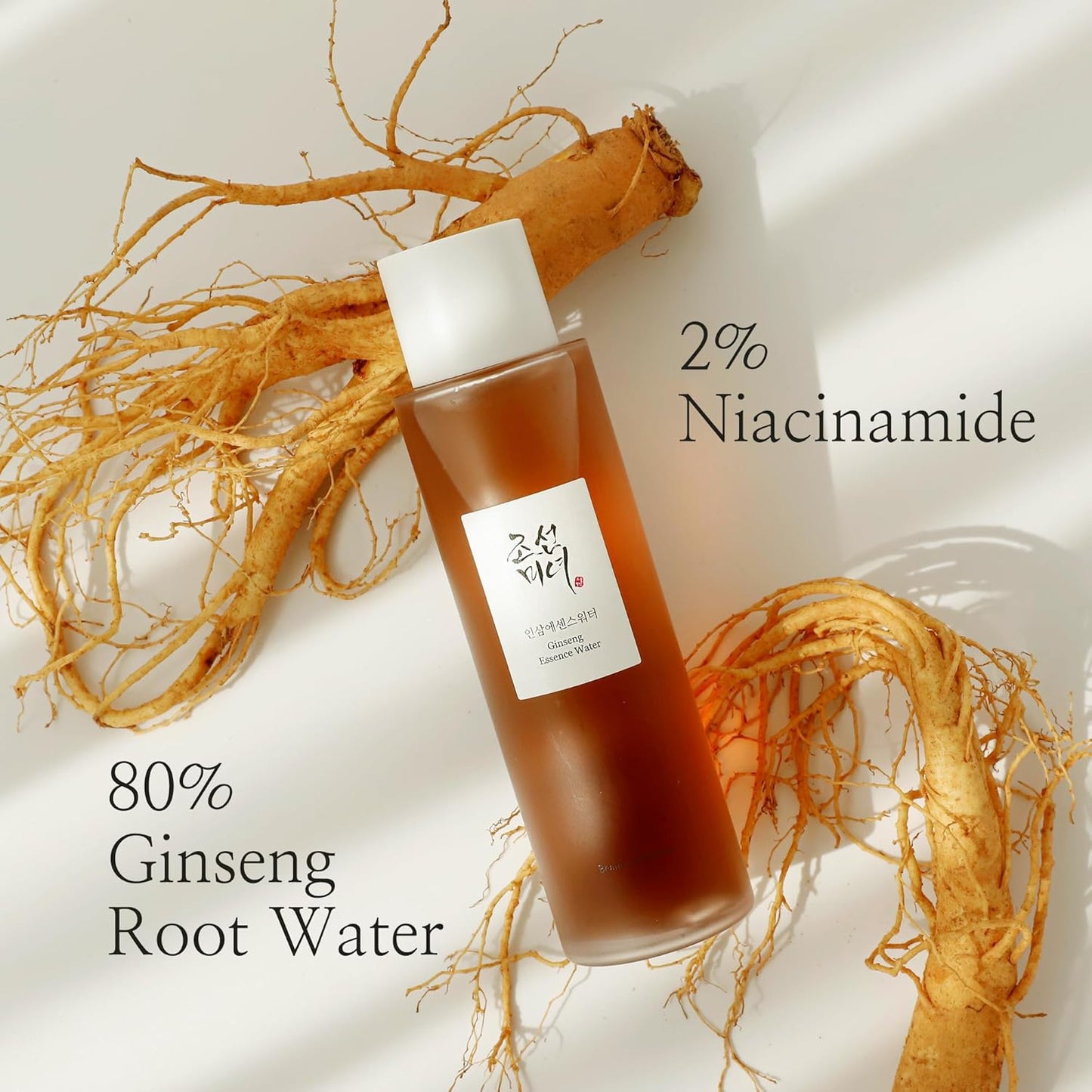 The Beauty of Joseon Ginseng Essence Water Toner, 150ml, features a brown bottle with a white cap and Korean label. Highlighting 80% Ginseng Root Water and 2% Niacinamide, its set among ginseng roots as a nod to Korean beauty rituals for glass skin in a brightly lit scene with soft shadows.