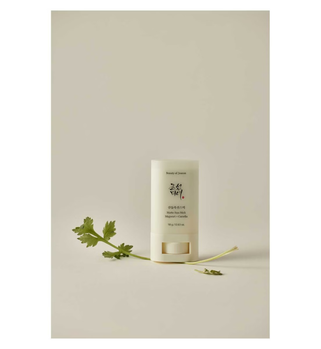 Skincare product with green leaves on a neutral background