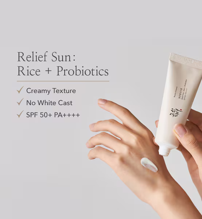 A hand dispenses white cream from a Beauty of Joseon Relief Sun: Rice + Probiotics SPF50+ PA++++ tube. Enjoy creamy texture, no white cast, and gentle sun protection with rice extract in this Korean sunscreen.