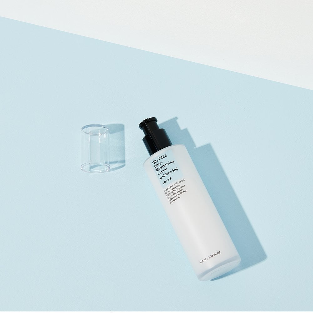 The COSRX Oil-Free Ultra Moisturizing Lotion, presented in a white bottle with birch sap, lies on a light blue and white surface. It features a black pump and clear cap, positioned diagonally as it casts a gentle shadow—perfect for clean beauty acne care from the brand COSRX.