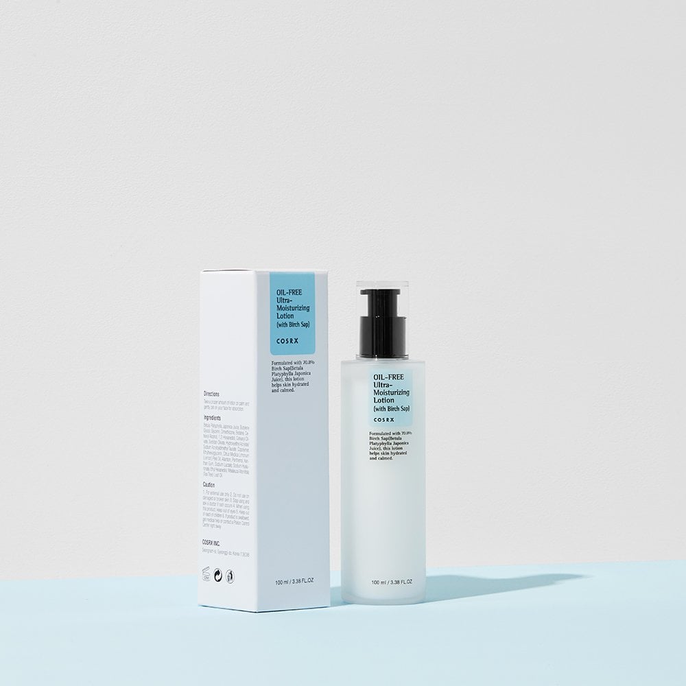 A bottle of COSRX Oil-Free Ultra Moisturizing Lotion (with Birch Sap), an ideal acne facial moisturizer, stands beside its box. The bottle has a black pump, and the predominantly white box features blue accents against a pale blue and white background, embodying clean beauty elegance.