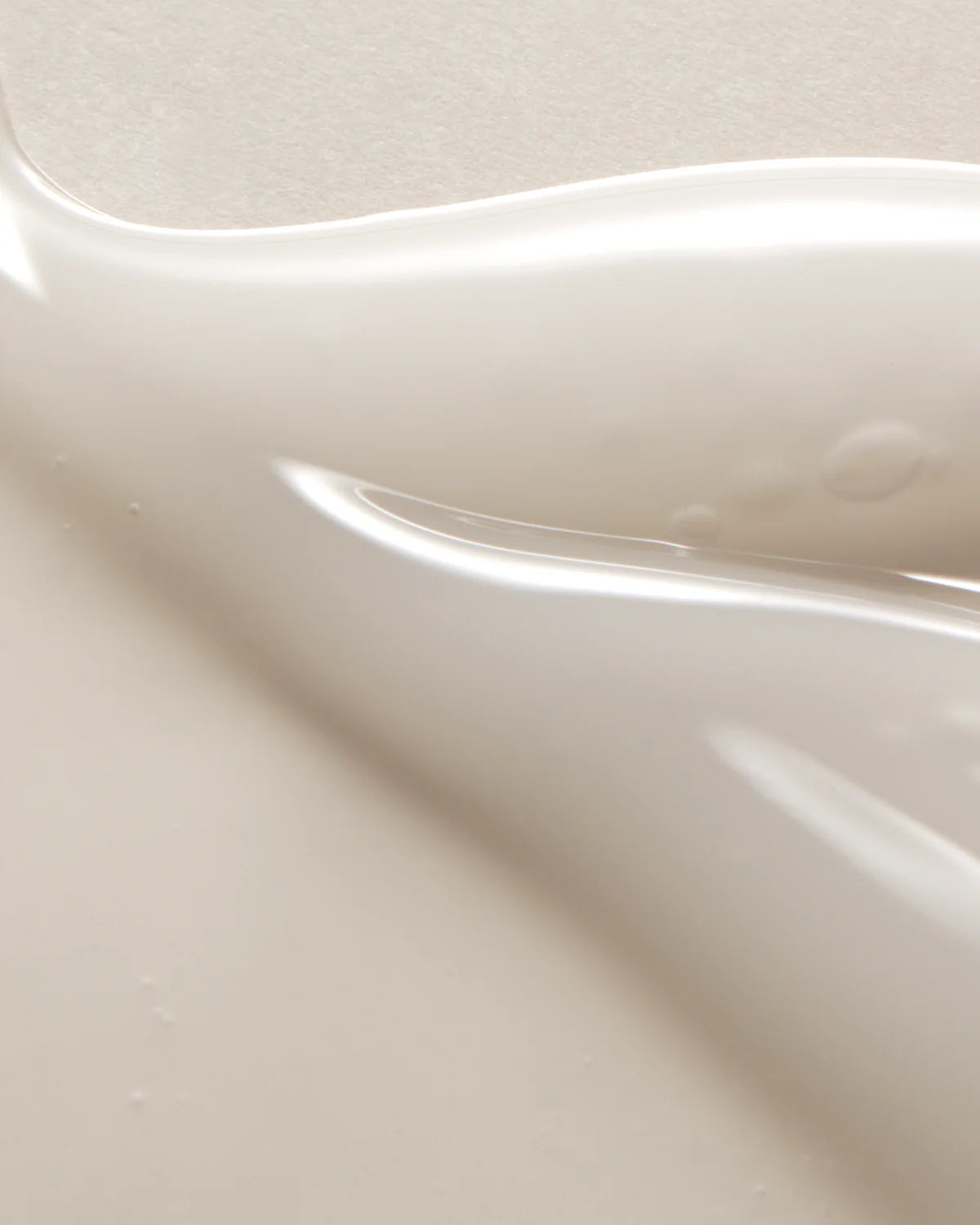 A close-up image reveals a smooth, creamy beige liquid with soft waves and light reflections, representing the fluidity of the AXIS-Y Dark Spot Correcting Glow Serum 50ml by AXIS-Y—an ideal choice for diminishing dark spots and enhancing your glow.