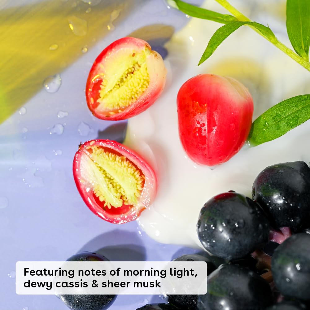 Close-up of sliced red grapes, whole dark grapes, green leaves, and creamy white lotion. Text overlay: Fresh + Cozy—featuring notes of morning light, dewy cassis & sheer musk in eos Shea Better 24H Body Lotion (473ml).