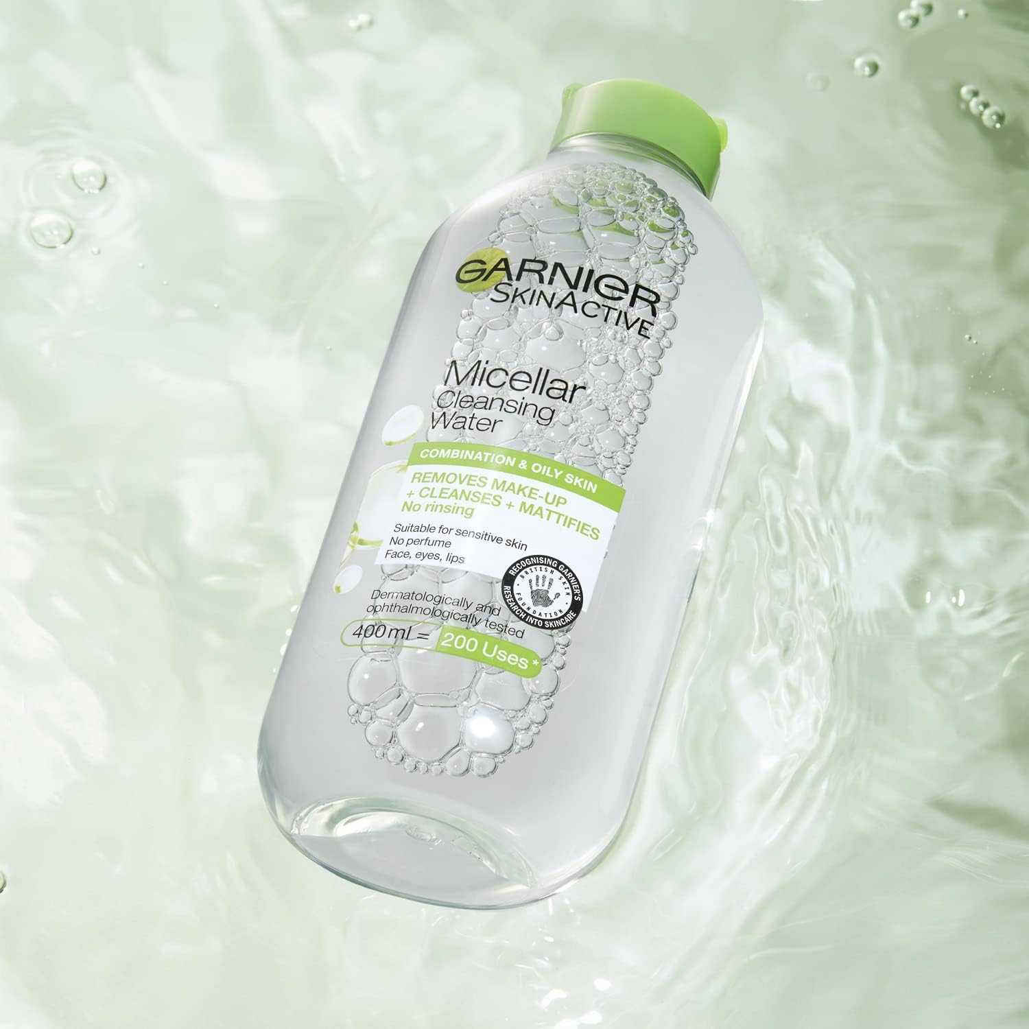 A bottle of Garnier Micellar Cleansing Water, a premier makeup remover for combination and oily skin, floats on rippled light green water. The transparent bottle with a green cap highlights its no-rinse formula.
