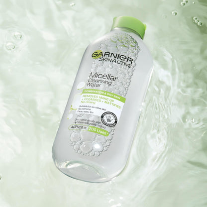 A bottle of Garnier Micellar Cleansing Water, a premier makeup remover for combination and oily skin, floats on rippled light green water. The transparent bottle with a green cap highlights its no-rinse formula.