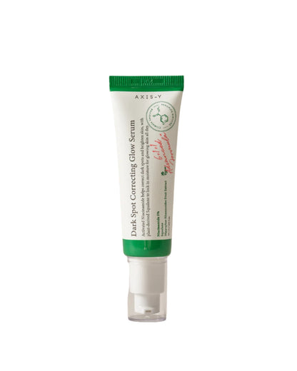 A small tube with a green cap contains AXIS-Y Dark Spot Correcting Glow Serum 50ml, enriched with niacinamide. The white tube features green and red text, minimalist design elements, and product information on the label.