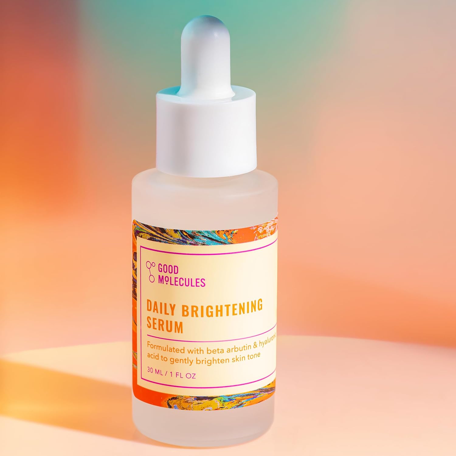 A 30ml bottle of Good Molecules Daily Brightening Serum sits against a vibrant multicolored background, showcasing its brightening benefits with ingredients like beta arbutin and hyaluronic acid.