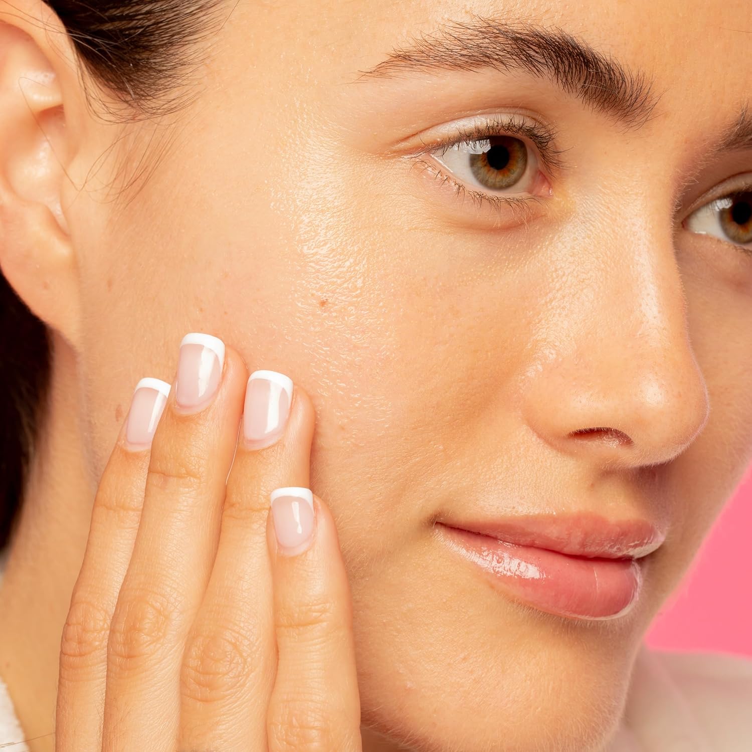 A woman with clear skin touches her cheek, showing off French-tip nails and natural makeup. Against a pink background, she reveals her secret: Good Molecules Daily Brightening Serum 30ml for a radiant glow.