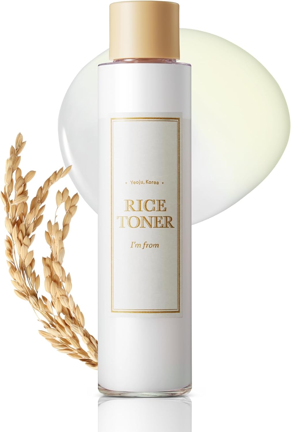 A 150ml bottle of IM FROM Rice Toner, with a gold cap, stands upright. The label reads Im From, Yeoju, Korea. Displayed artistically beside it are hydrating rice extract and a cluster of rice grains.