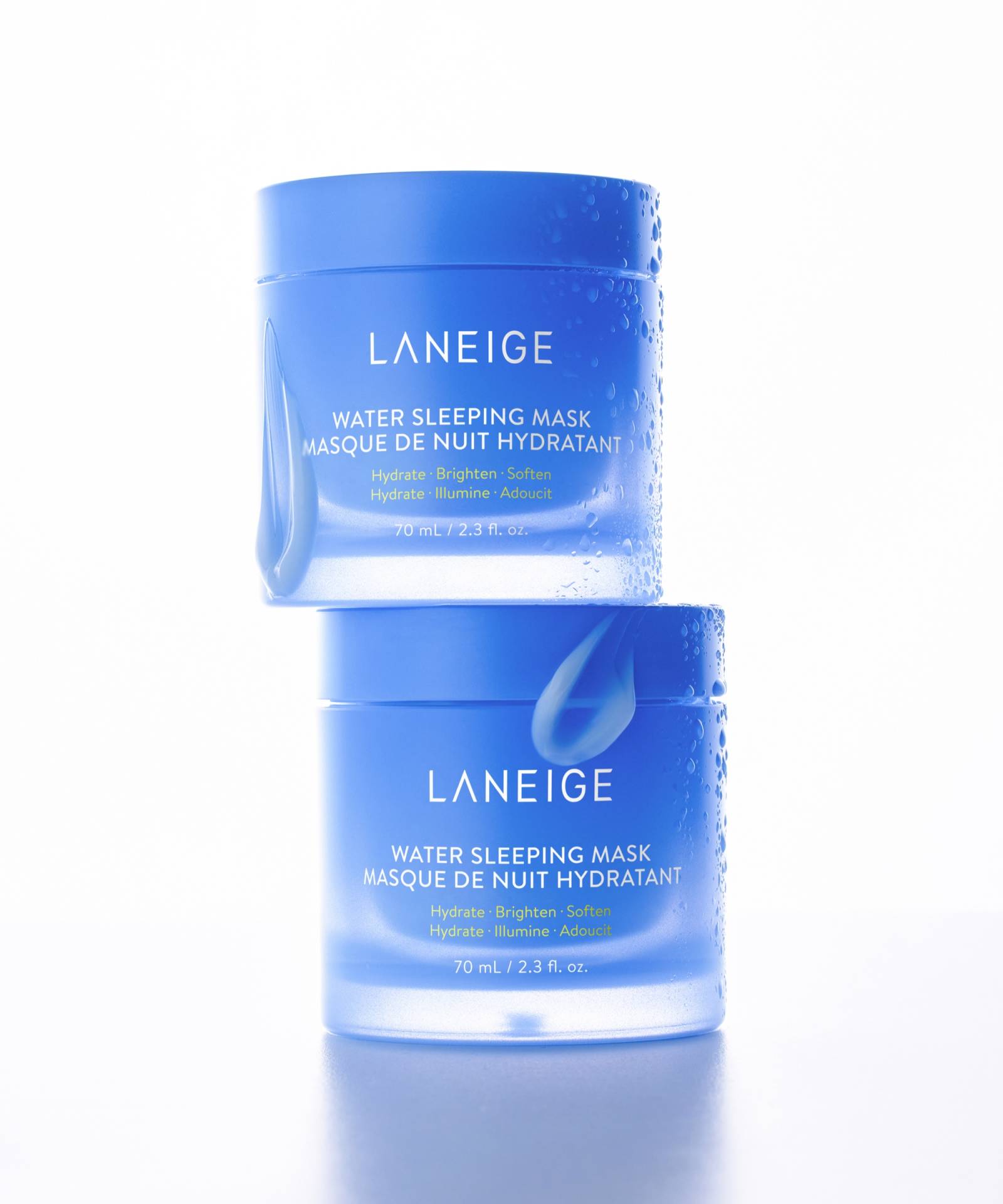 Two blue jars of LANEIGE Water Sleeping Mask are stacked, highlighting their hydrating and brightening features. Each 70ml jar, enhanced with probiotics-derived complex, offers a softening overnight mask with text in English and French for an elevated skincare routine.