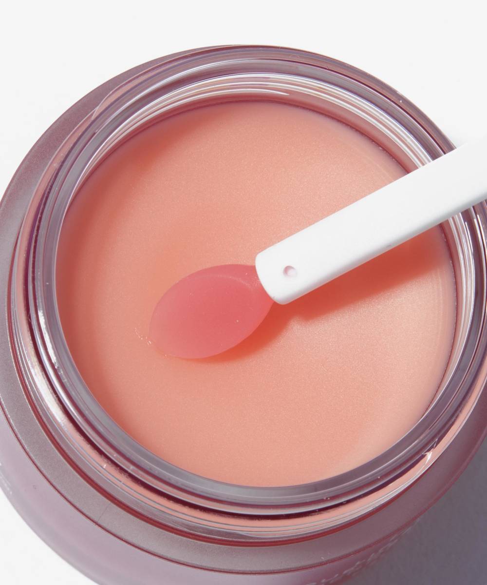 A close-up of an open Laneige Lip Sleeping Mask - BERRY 20g jar, featuring a small white spatula on the edge. The LANEIGE nourishing balm enriched with vitamin C displays its smooth, glossy texture against a plain white background.