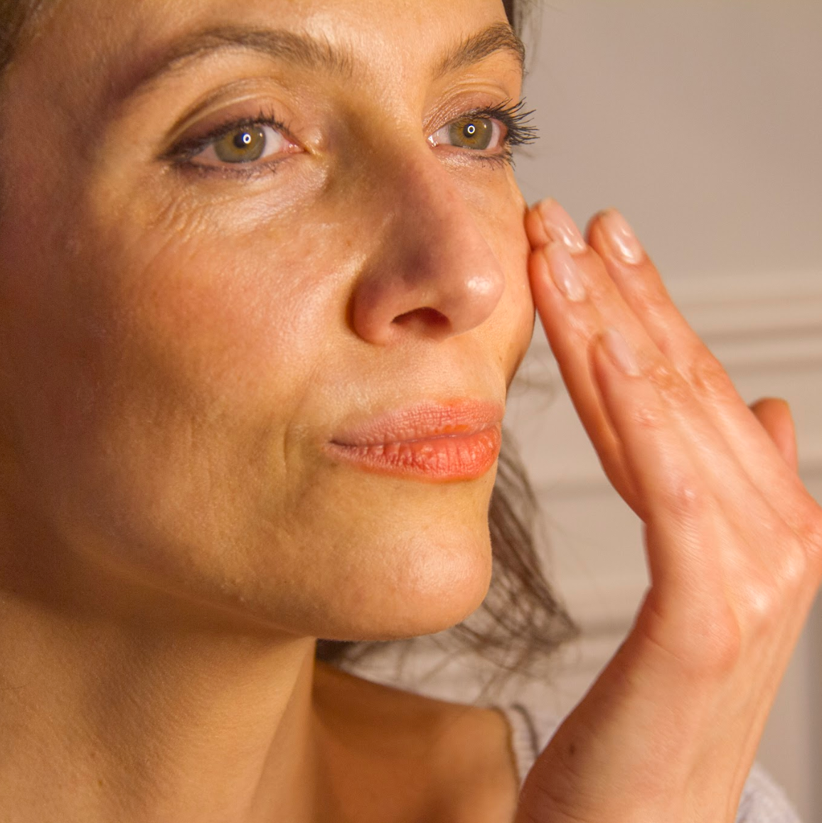 Woman touching her face with a neutral background