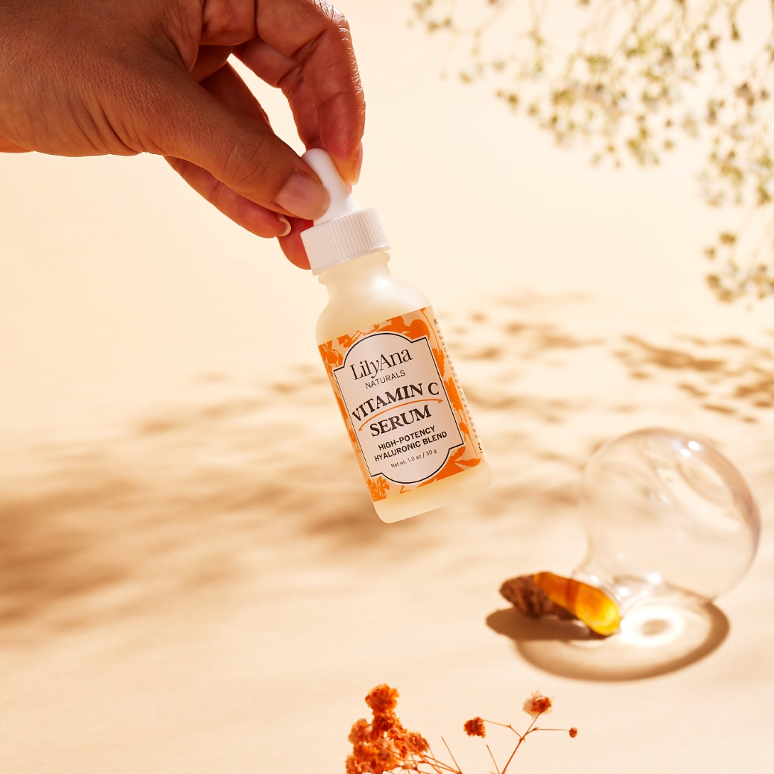 Hand holding a bottle of LilyAna Vitamin C Serum with a blurred natural background