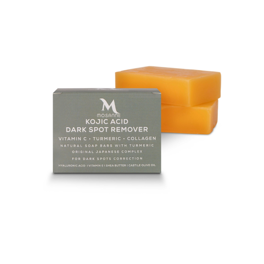 A box labeled MOSANNE Kojic Acid Dark Spot Remover Soap - 2 pack is in the foreground, featuring skin-brightening ingredients like Vitamin C and turmeric. Behind it, two orange soap bars are stacked, enhancing this dark spot correctors powerful formula.