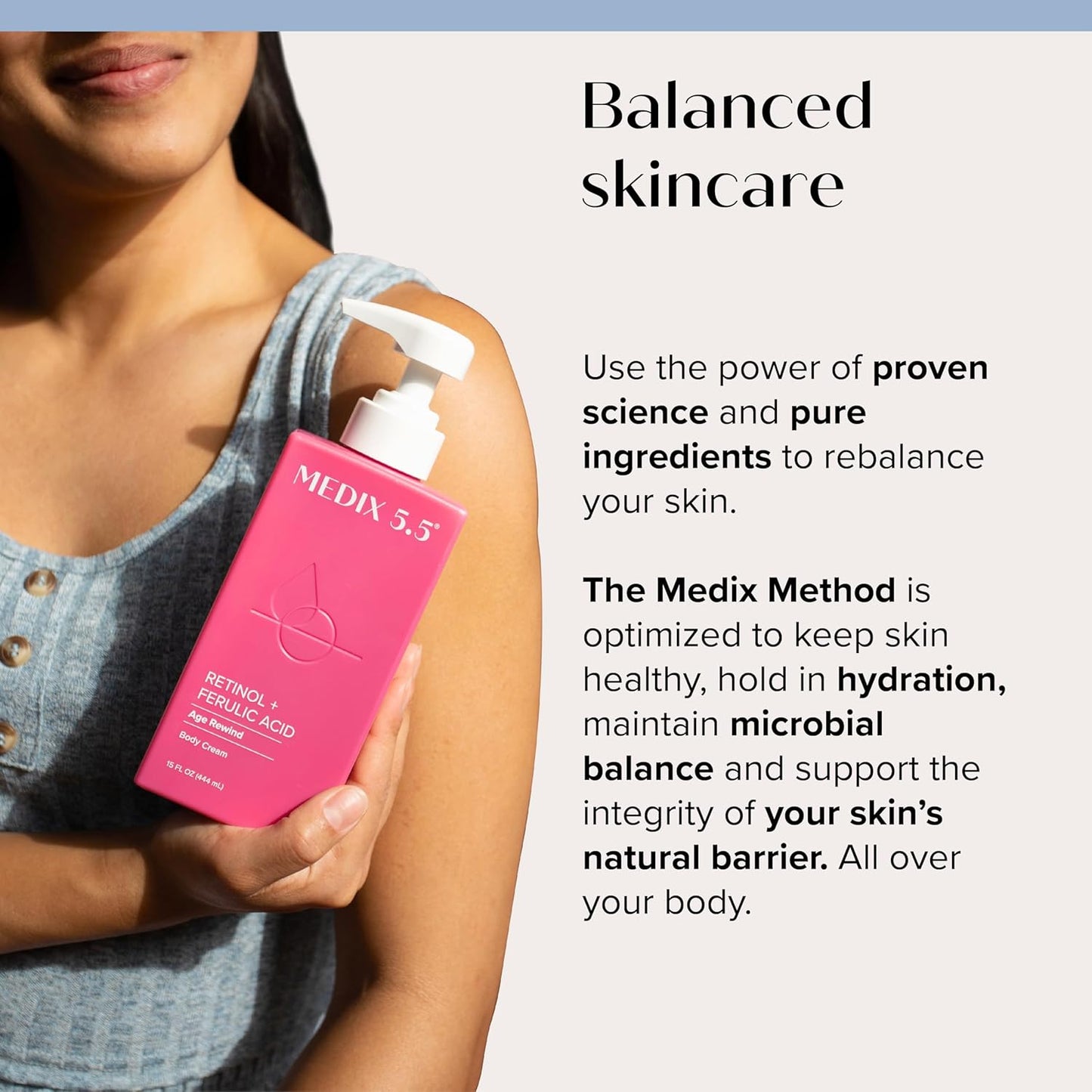 A person in a denim top holds a pink MEDIX 5.5 Body Cream bottle with Retinol + Ferulic Acid and a pump dispenser, highlighting its anti-aging ingredients for collagen production, balanced skincare, and deep hydration for microbial balance.