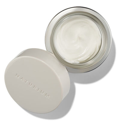 Open jar of cream with lid on a white background, featuring the brand 'Naturium'.