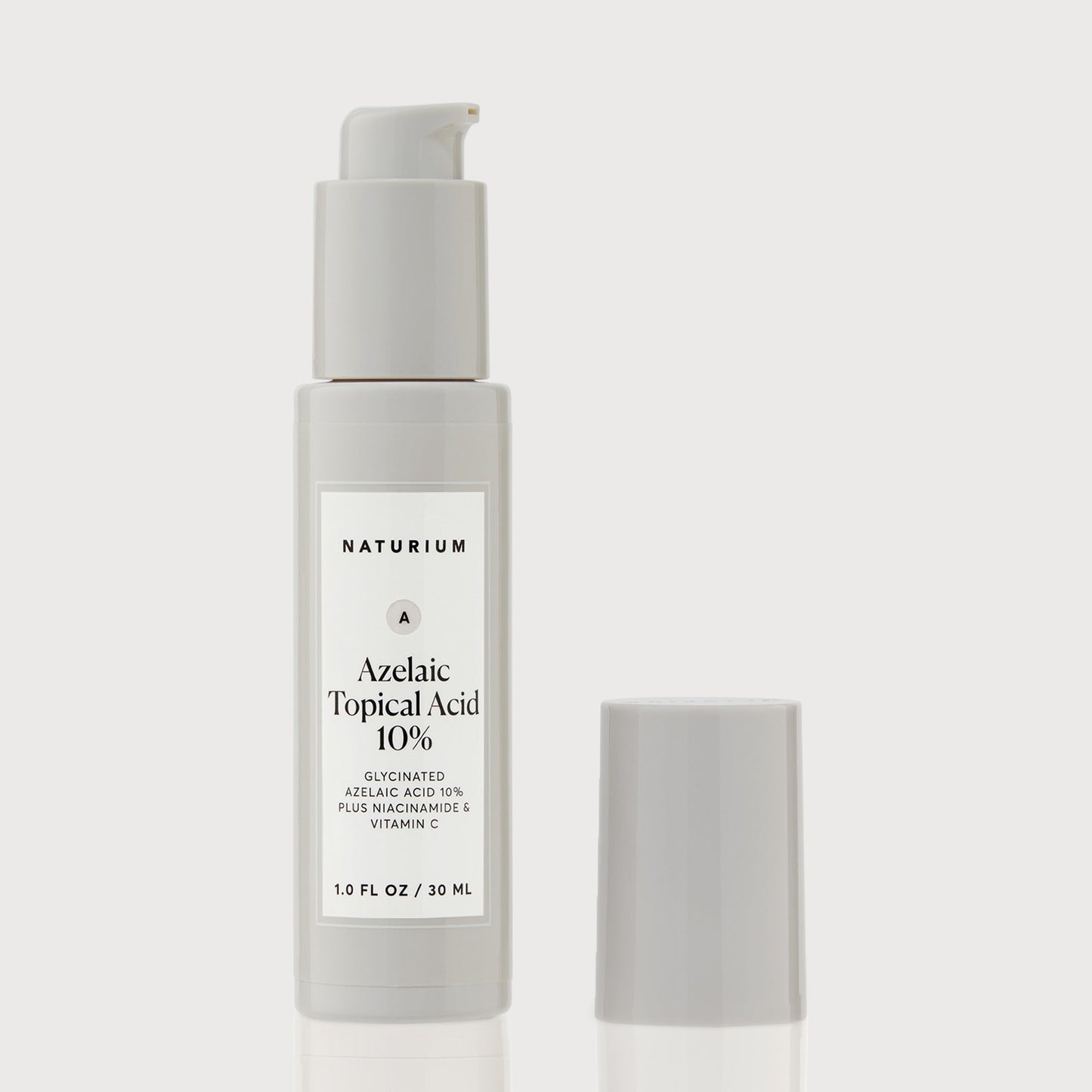 A white bottle of NATURIUM Azelaic Acid 10% (30ml) – Brightening & Texture Refining Serum with a pump and gray cap; label highlights azelaic acid, niacinamide, and vitamin C for brightening uneven skin tone.