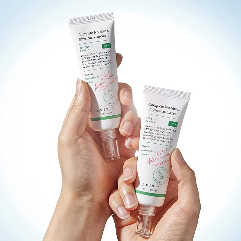 Each hand holds a tube of Axis-Y Complete No-Stress Physical Sunscreen 50ml by AXIS-Y, featuring soothing benefits. The white packaging with green accents offers SPF 50+ protection and includes niacinamide to enhance skin care, promising to soothe while shielding against UVA/UVB rays.
