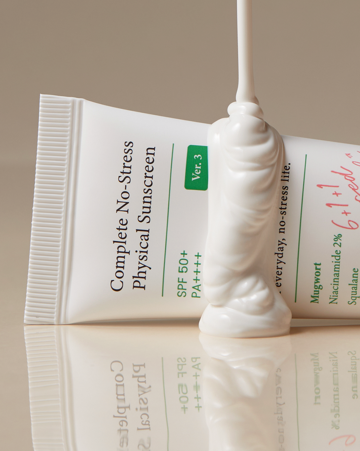 A tube of creamy sunscreen, labeled Axis-Y Complete No-Stress Physical Sunscreen by AXIS-Y, flows thickly with SPF 50+ and PA++++ ratings, enriched with niacinamide. It rests on a smooth beige background.