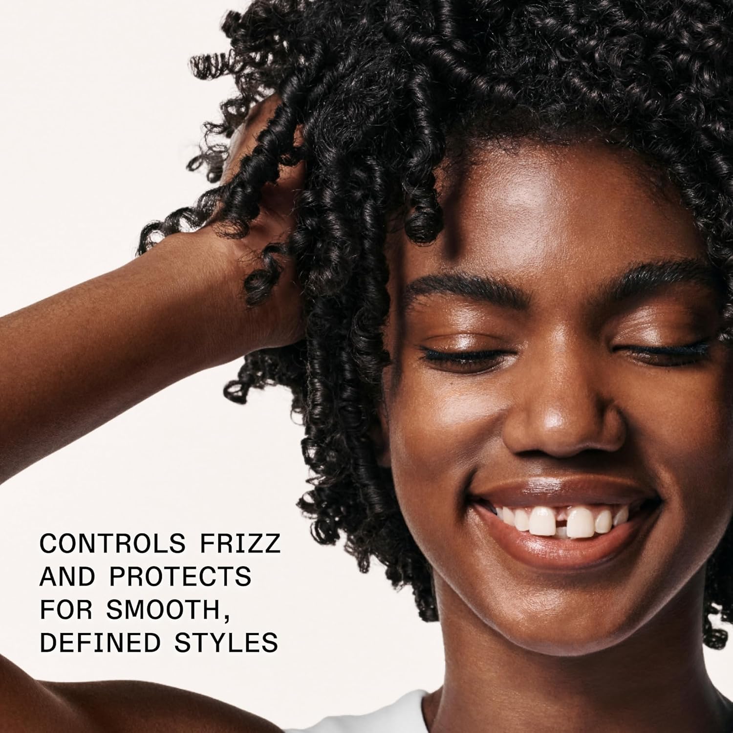 A smiling woman with shiny, defined curls touches her head. The text reads: OLAPLEX No.6 Bond Smoother Leave In Treatment controls frizz and flyaways for smooth, healthy styles. Her healthy hair shines after using OLAPLEX.