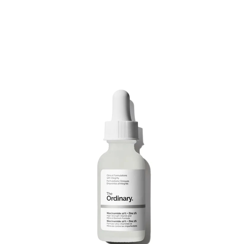A translucent dropper bottle of The Ordinary Niacinamide 10% + Zinc 1% 30ml serum sits on a white background. Ideal for blemish-prone skin, it features a white label with black text and a sleek white dropper cap.