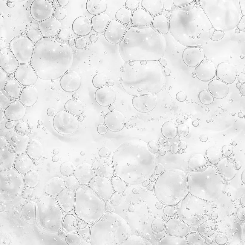 A close-up of transparent bubbles on a smooth white surface resembles the textured effect of The Ordinary Niacinamide 10% + Zinc 1% serum for blemish-prone skin, where varied bubble sizes create a frothy appearance.