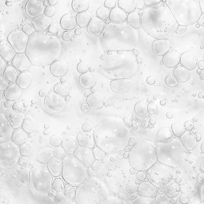 A close-up of transparent bubbles on a smooth white surface resembles the textured effect of The Ordinary Niacinamide 10% + Zinc 1% serum for blemish-prone skin, where varied bubble sizes create a frothy appearance.